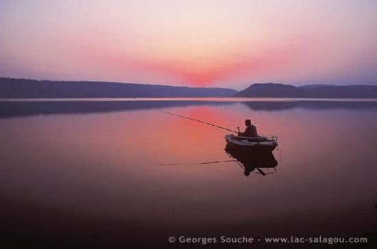 pêcheur de carpes au coucher de soleil sur le lac